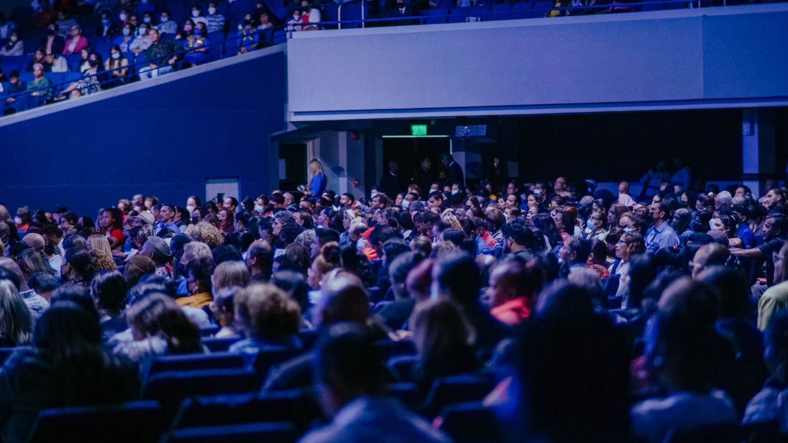 Large auditorium filled with an audience listening to a speaker