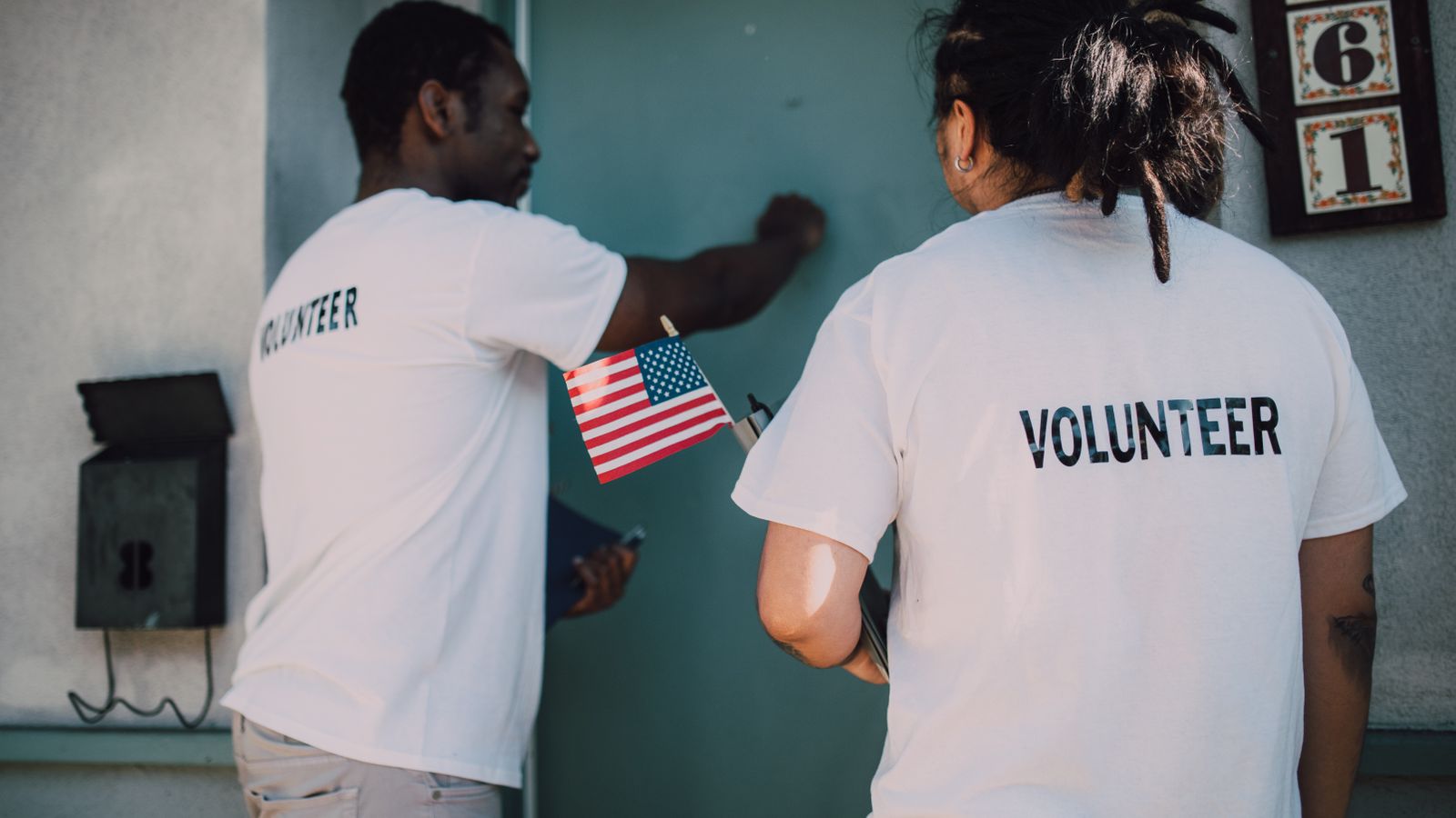 Volunteers in matching shirts holding a small American flag at a community event