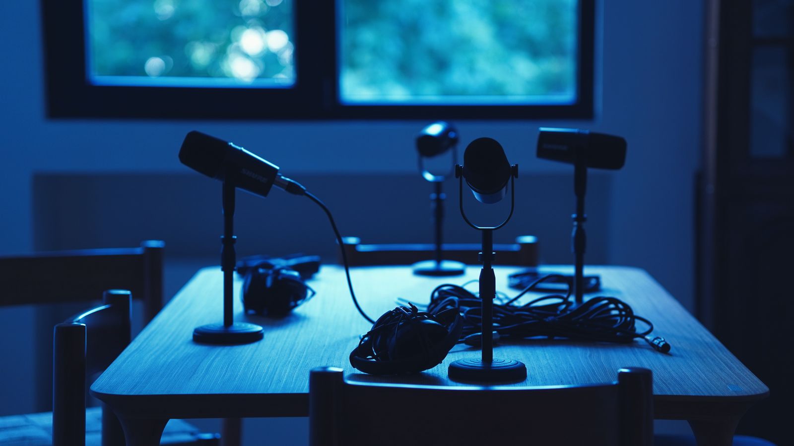 Podcast studio with microphones and headphones lit in blue