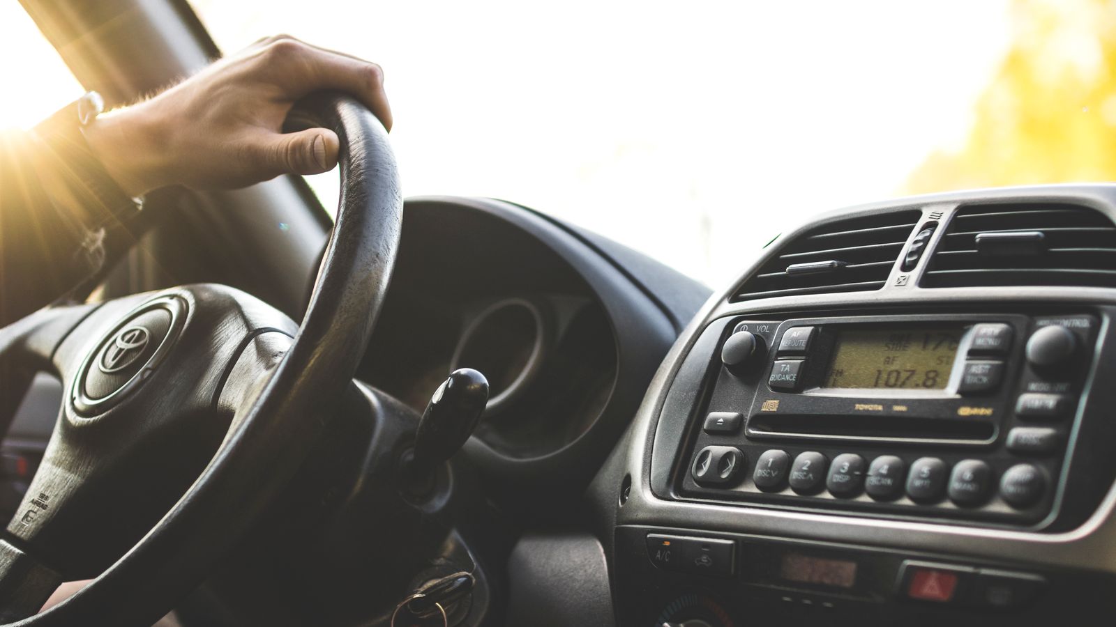 Driver at the wheel with the car stereo tuned to a local FM station